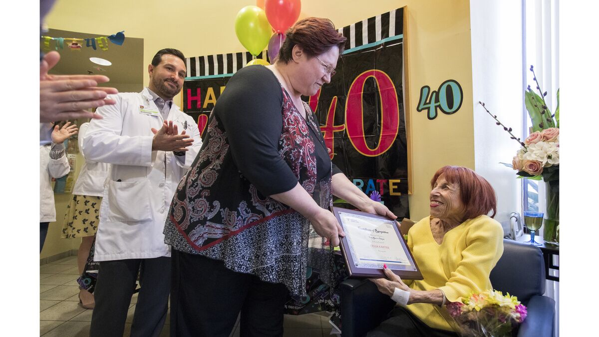 Edda Spinelli, regional director of operations for Avantus Renal Therapy in Newport Beach, presents Celia Kanter, 77, with a certificate of recognition Friday for achieving the milestone of 40 years on dialysis.