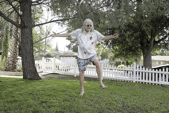 An animated GIF of Howard Mordoh dancing on a lawn with a white picket fence.