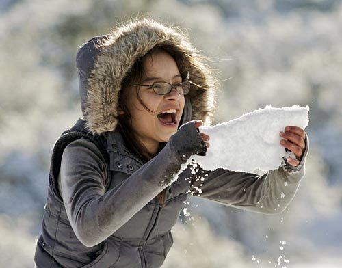 Rebekah Arroyo, 11, of Hesperia grabs a chunk of ice at Snow Summit along Cajon Pass in Oak Hill.