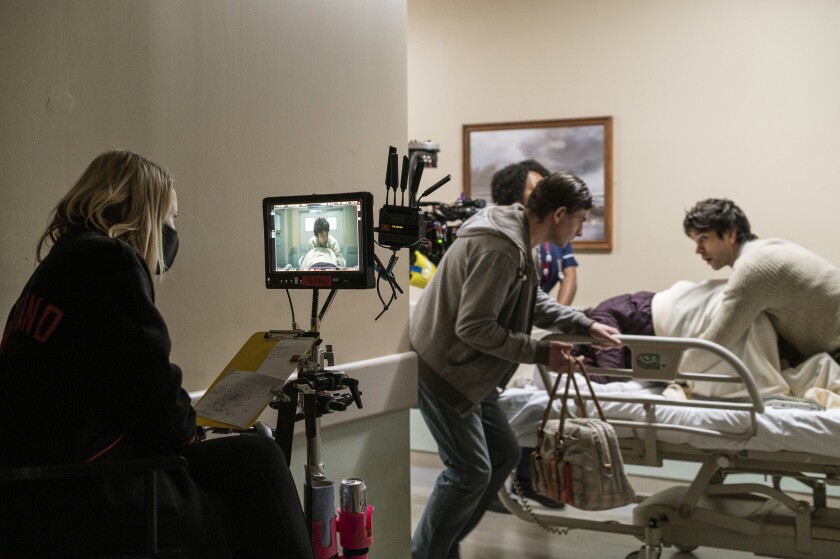 A camera crew shoots a scene of a woman in labor