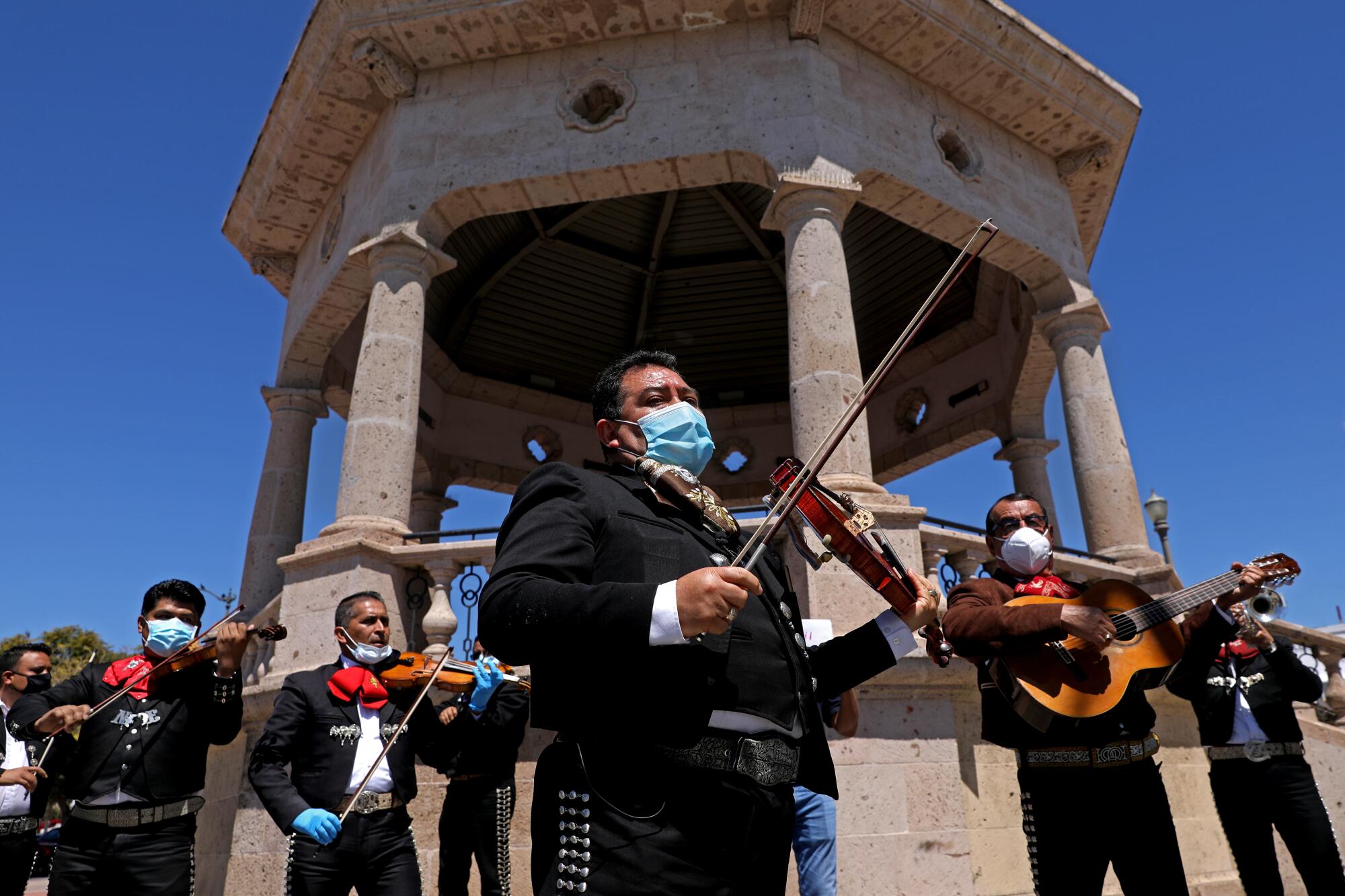 Israel Moreno, centro, José Cervantes, derecha, y otros músicos se unen en solidaridad a Mariachi Plaza en Boyle Heights para pedir ayuda financiera a los funcionarios locales durante la pandemia.