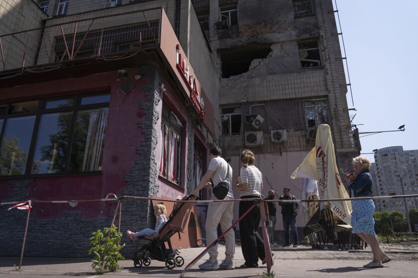People look at an apartment building damaged by a drone during a night attack in Kyiv, Ukraine, Sunday, May 28, 2023. Ukraine's capital was subjected to the largest drone attack since the start of Russia's war, local officials said, as Kyiv prepared to mark the anniversary of its founding on Sunday. (AP Photo/Vasilisa Stepanenko)