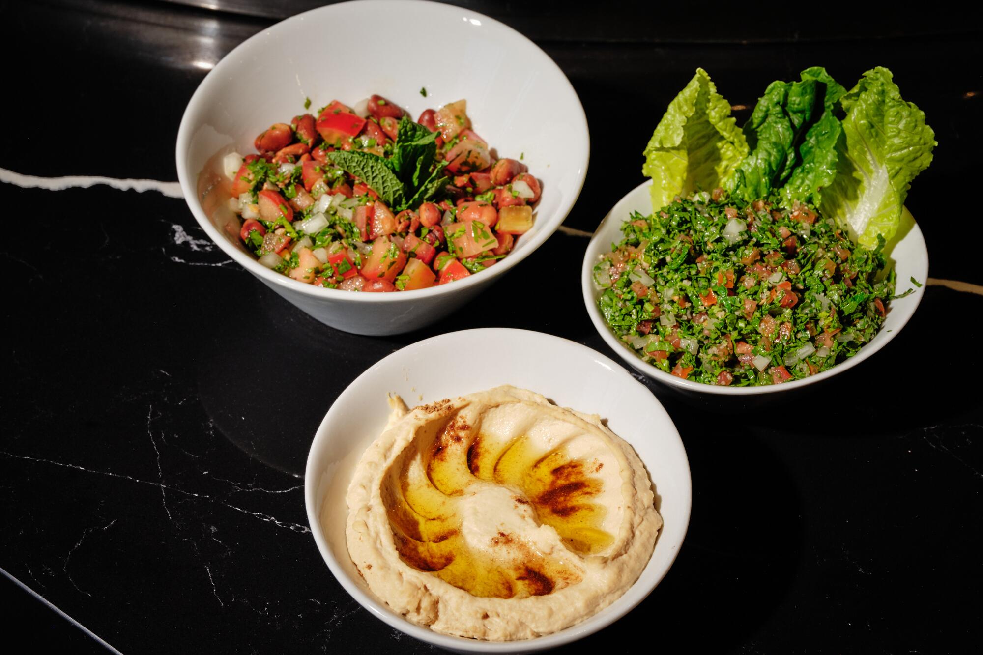 Sides of ful medames (top left), tabouleh (right), and hummus (bottom) Shawarma.