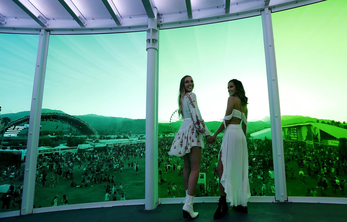 Festival goers Sam Peraino, left, and Kayla Rover pose for pictures inside the "Spectra" as the sun sets on Day 1 of the Coachella Music and Arts Festival. (Luis Sinco / Los Angeles Times)