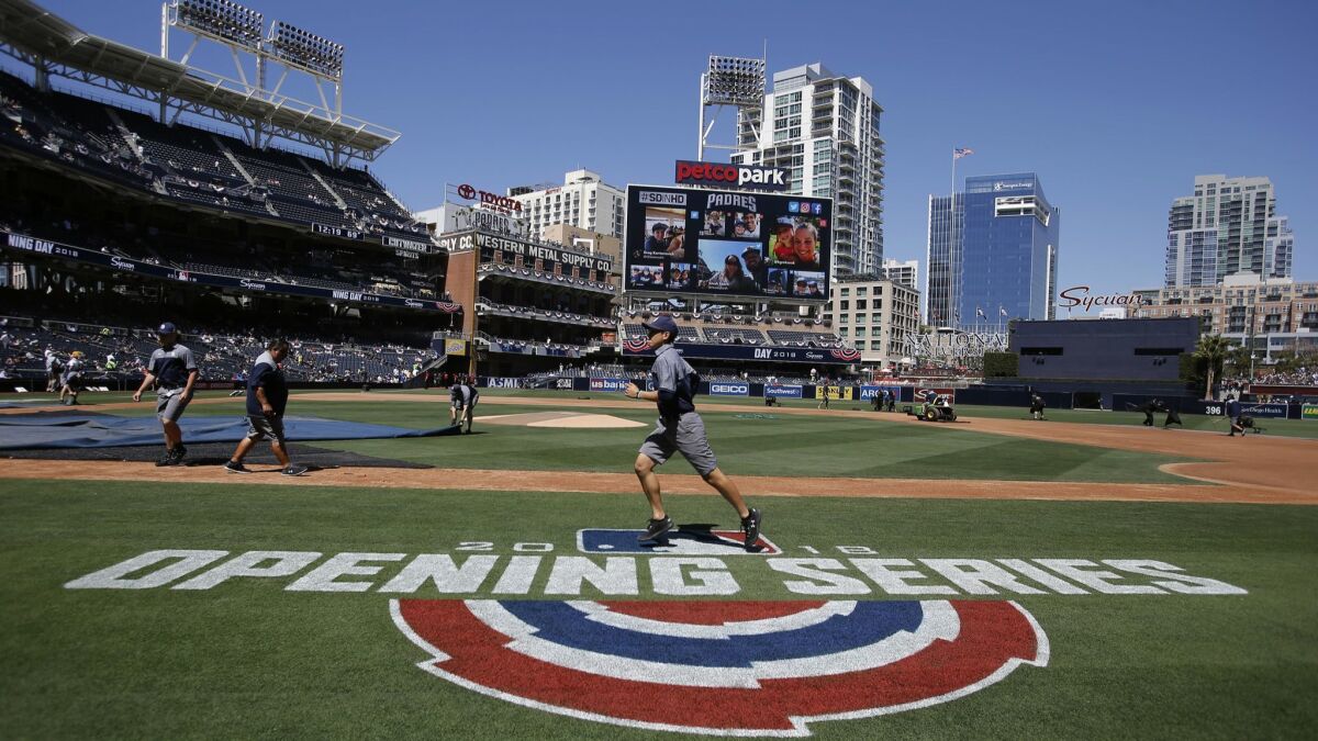 A groundskeeper runs over the logo before an opening day baseball game between the San Diego Padres and the Milwaukee Brewers in San Diego,