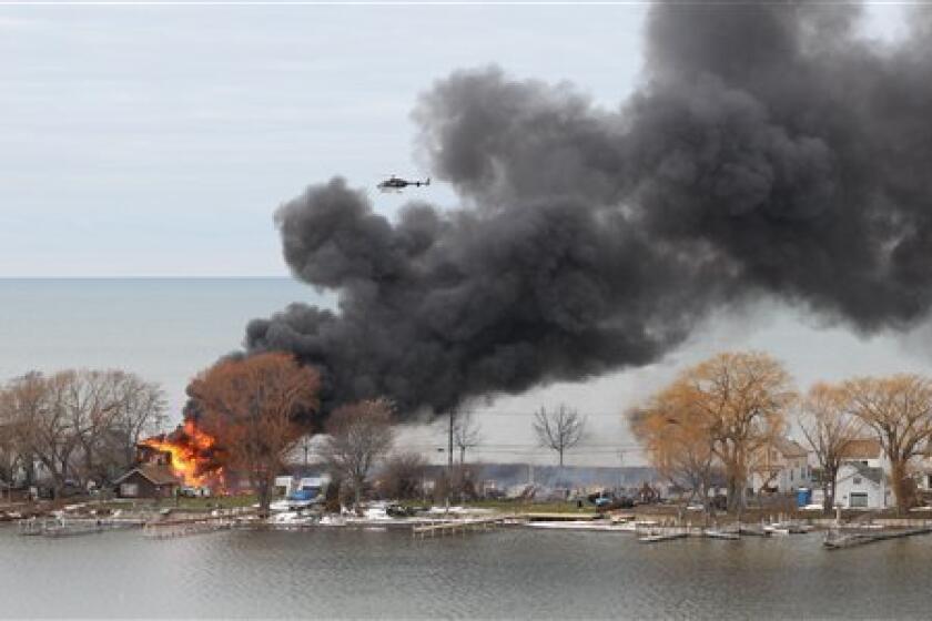 A house burns in Webster, N.Y., after an ex-convict set a car ablaze in his lakeside neighborhood to lure firefighters, then opened fire. He killed two and seriously wounded two more before killing himself.
