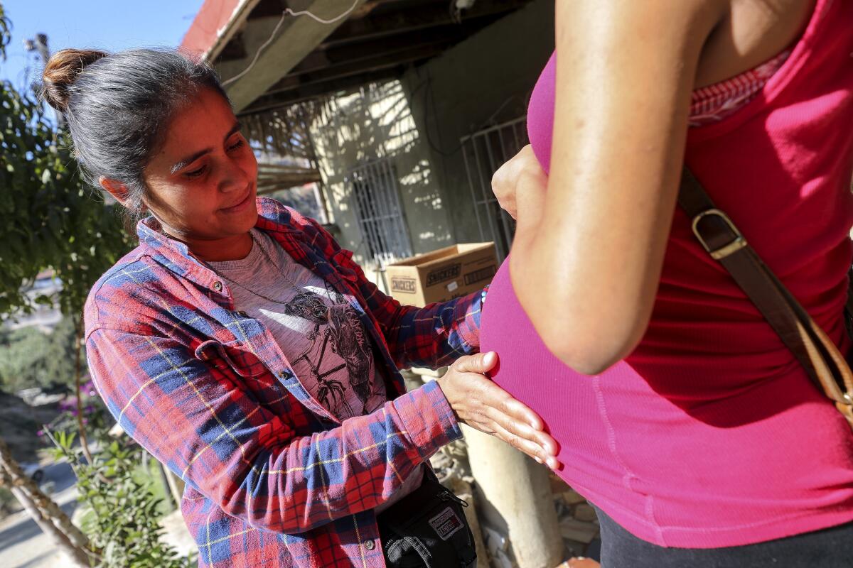 Yenni López, de 33 años, toca el estómago de una mujer embarazada de Guatemala mientras está fuera de Tu Casa, un hogar para migrantes centroamericanos, en Tijuana, México, el jueves 14 de noviembre de 2019.