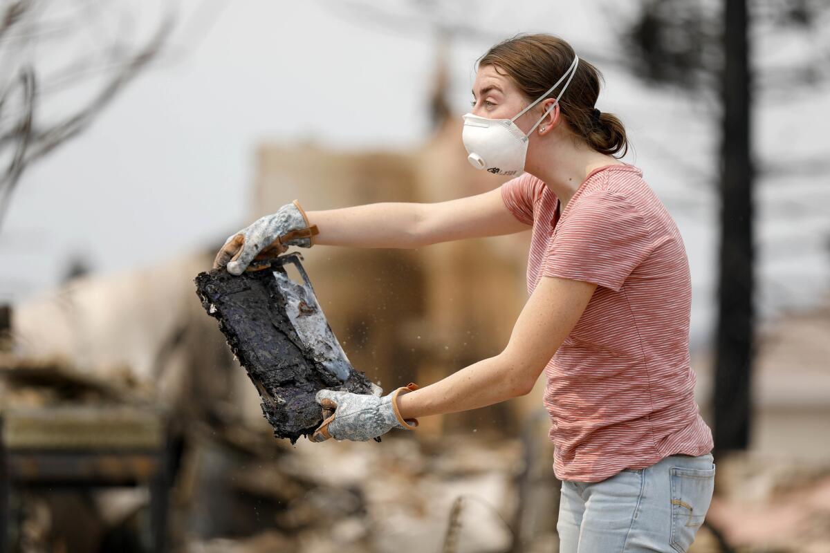 Morgan Gregory, 17, holds up her laptop at her home destroyed by the Carr fire. (Gary Coronado / Los Angeles Times)