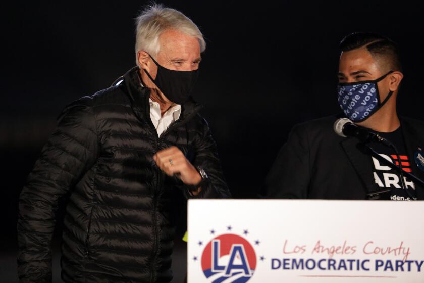 LOS ANGELES, CA - NOVEMBER 03: George Gascon, left, candidate for Los Angeles District Attorney is introduced by Mark Gonzalez, chair of the Los Angeles County Democratic Party, during a drive-in election night watch party at the LA Zoo parking lot on Tuesday, Nov. 3, 2020. (Myung J. Chun / Los Angeles Times)