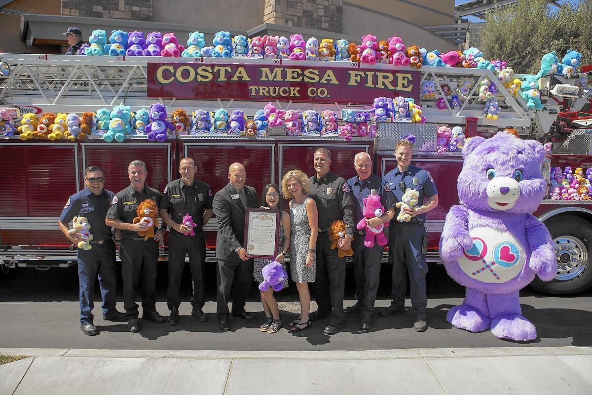 Tim Whitacre, of Supervisor Michelle Steel's office, Sandy Segerstrom, Costa Mesa Fire Chief Dan Stefano and firefighters pose with Jessica Carscadden,13, the founder of We Care Bears on Friday.