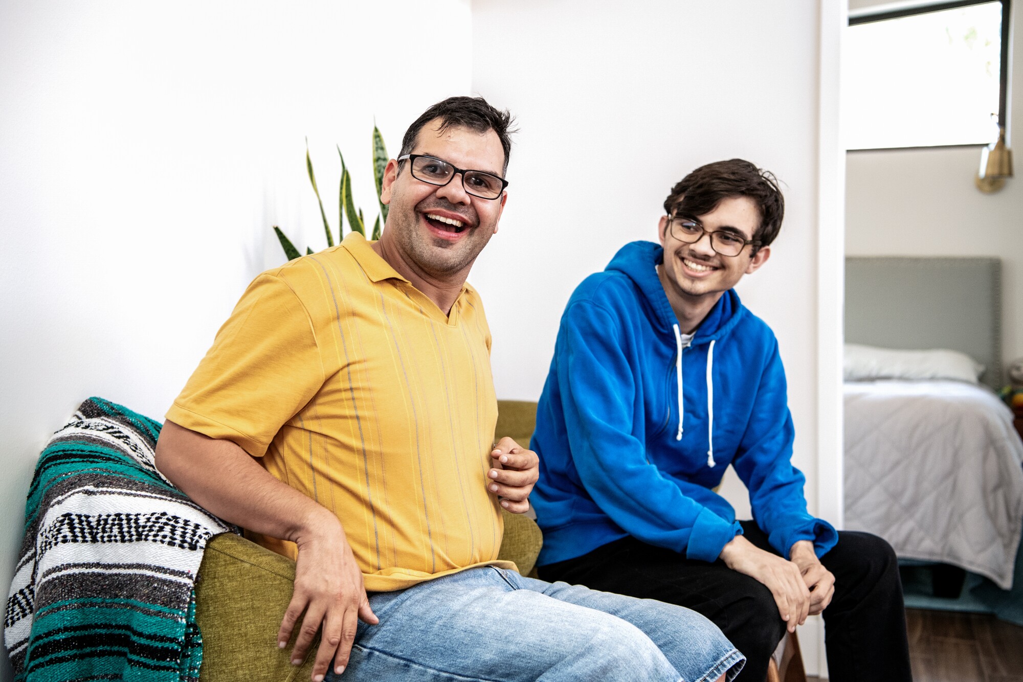 Two brothers sit next to each other smiling.