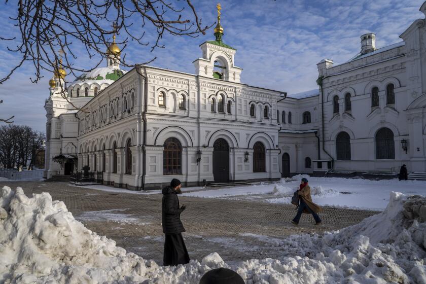 FILE - A monk and a woman walk inside the Pechersk Lavra monastic complex in Kyiv, Ukraine, on Dec. 1, 2022. Ukrainian Minister of Culture Oleksandr Tkachenko said Thursday Jan. 5. 2023 that the Dormition Cathedral and the Refectory Church of the nearly 1,000-year-old Pechersk Lavra in the Ukrainian capital have been taken over by the state after the lease of them held by the Ukrainian Orthodox Church expired on Dec. 31. (AP Photo/Bernat Armangue, File)