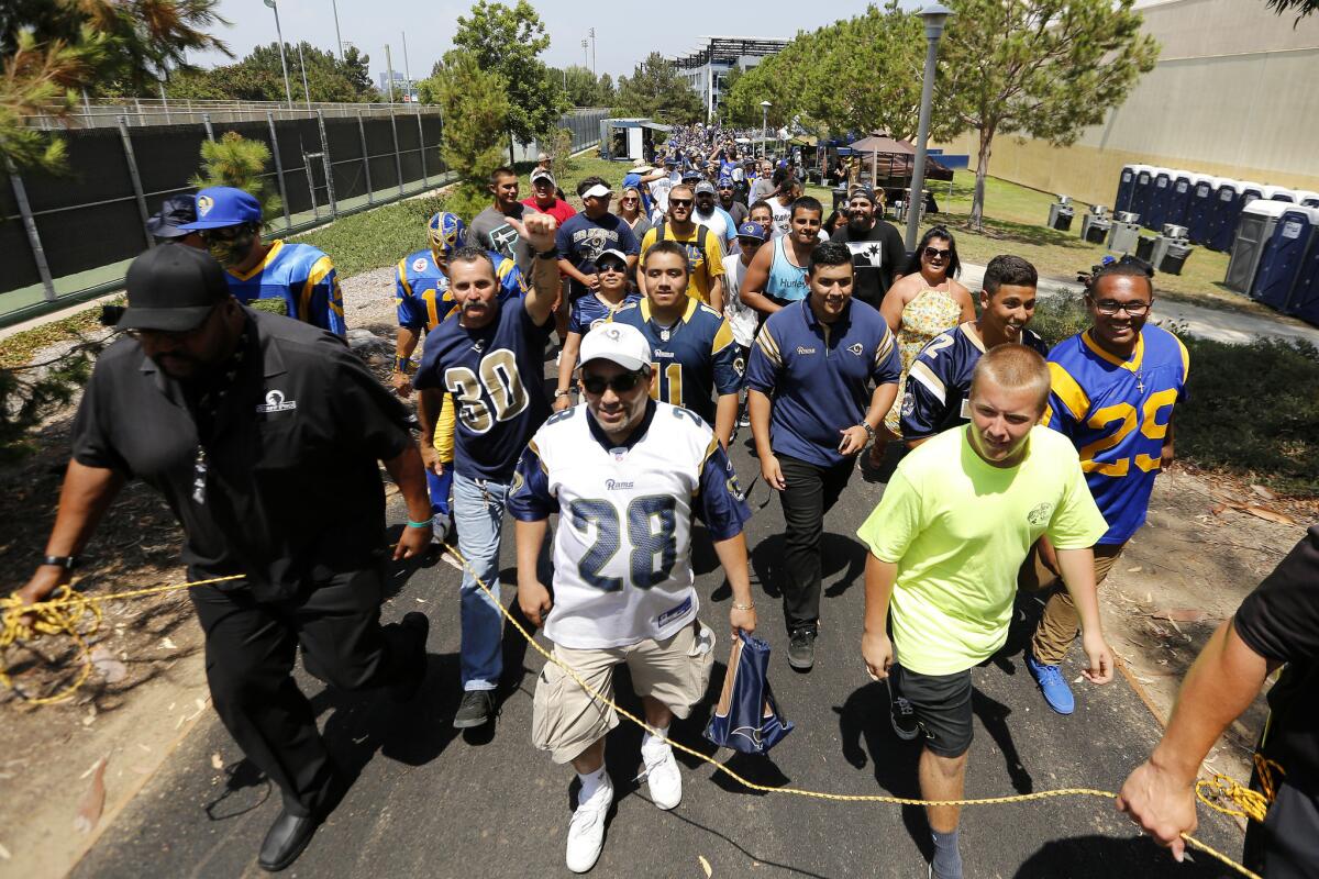 Security staff escort fans to the practice field during Rams training camp at UC Irvine on Saturday.