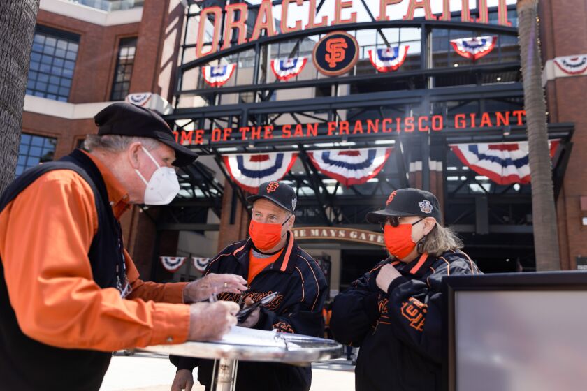 SAN FRANCISCO, CALIFORNIA - APRIL 09: San Francisco Giants fans Dave Harding of San Leandro, center, and his wife, Nancy Faltisek, check in at one of the vaccination/negative test verification booths to show the proof of their COVID-19 vaccinations before being admitted to Oracle Park at the Giants’ season home opener on Friday, April 9, 2021, in San Francisco, Calif. (Dai Sugano/Bay Area News Group)