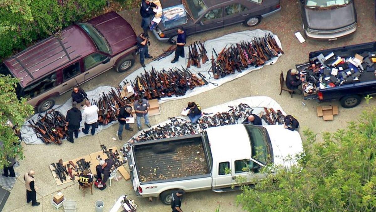 Investigators inspect a large cache of weapons seized at a Bel-Air home in May.
