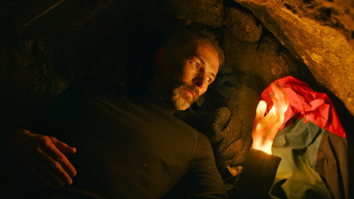 A man in a cave finds his hand glowing.
