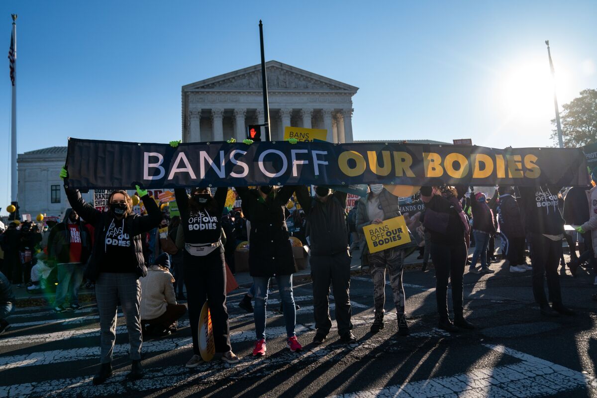 Protesters outside the Supreme Court hold a banner reading "Bans Off Our Bodies."