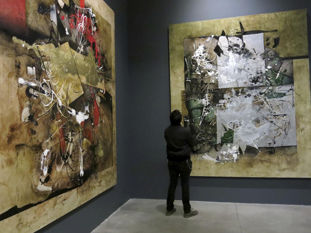 A man stands before two large abstract paintings by Mexican artist Manuel Felguérez at MUAC in Mexico City.