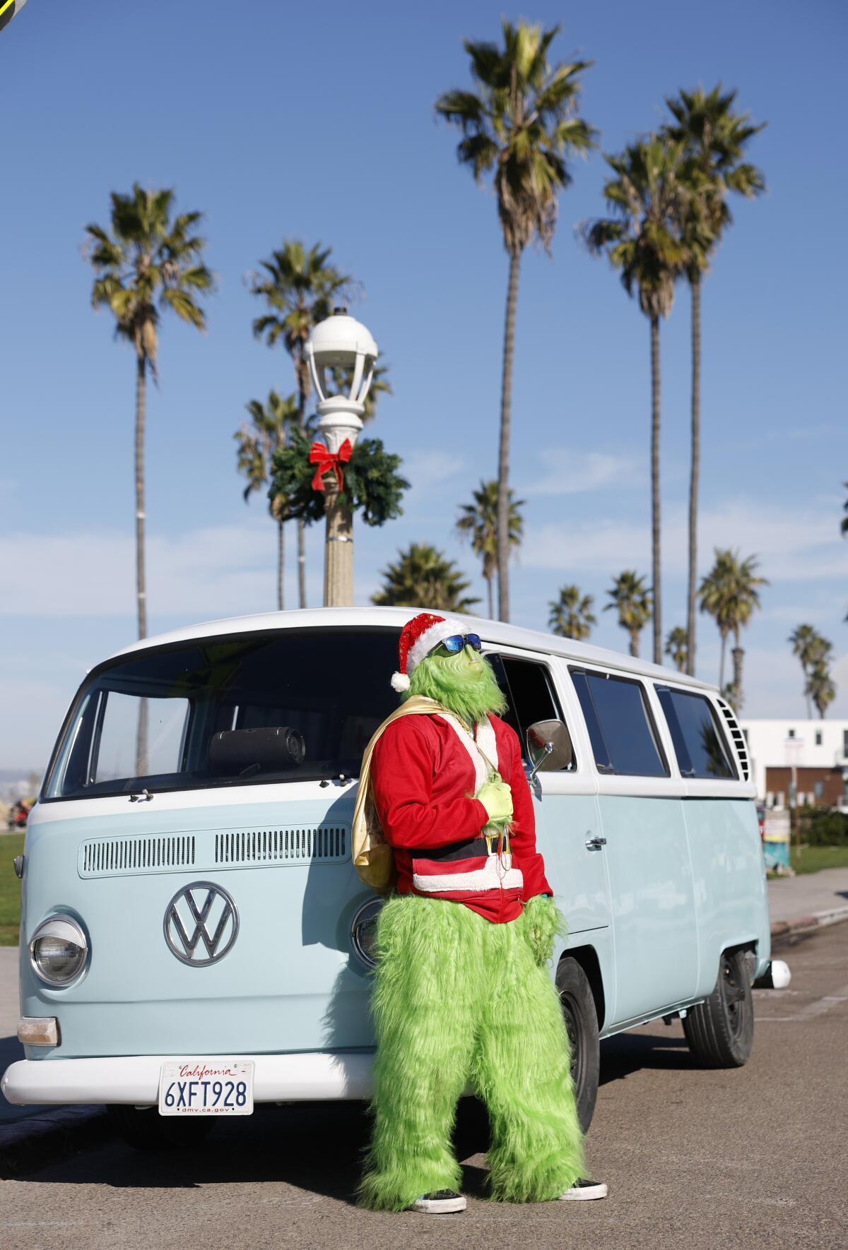Ryan Ortiz, dressed in a Grinch costume, stands next to his 1969 Volkswagen Bus