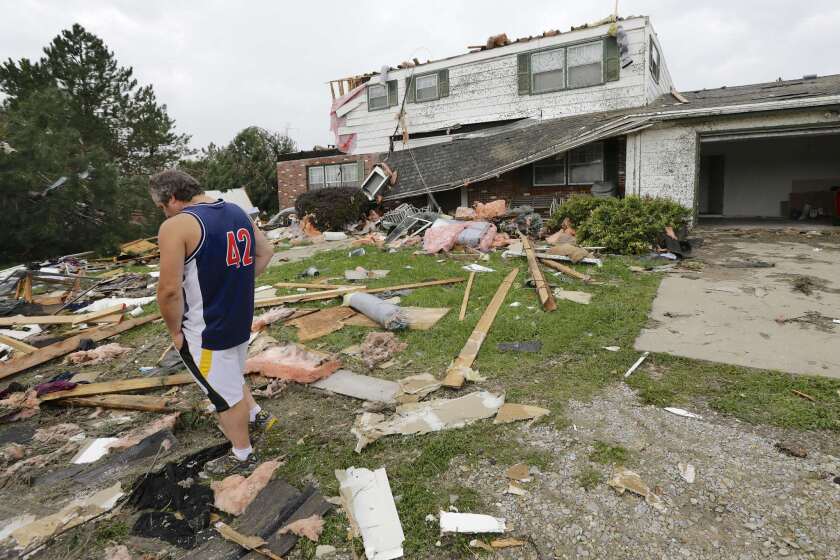 Travis Randall surveys the damage to his parents' home in Hickman, Neb., after a tornado tore through the town Thursday night.