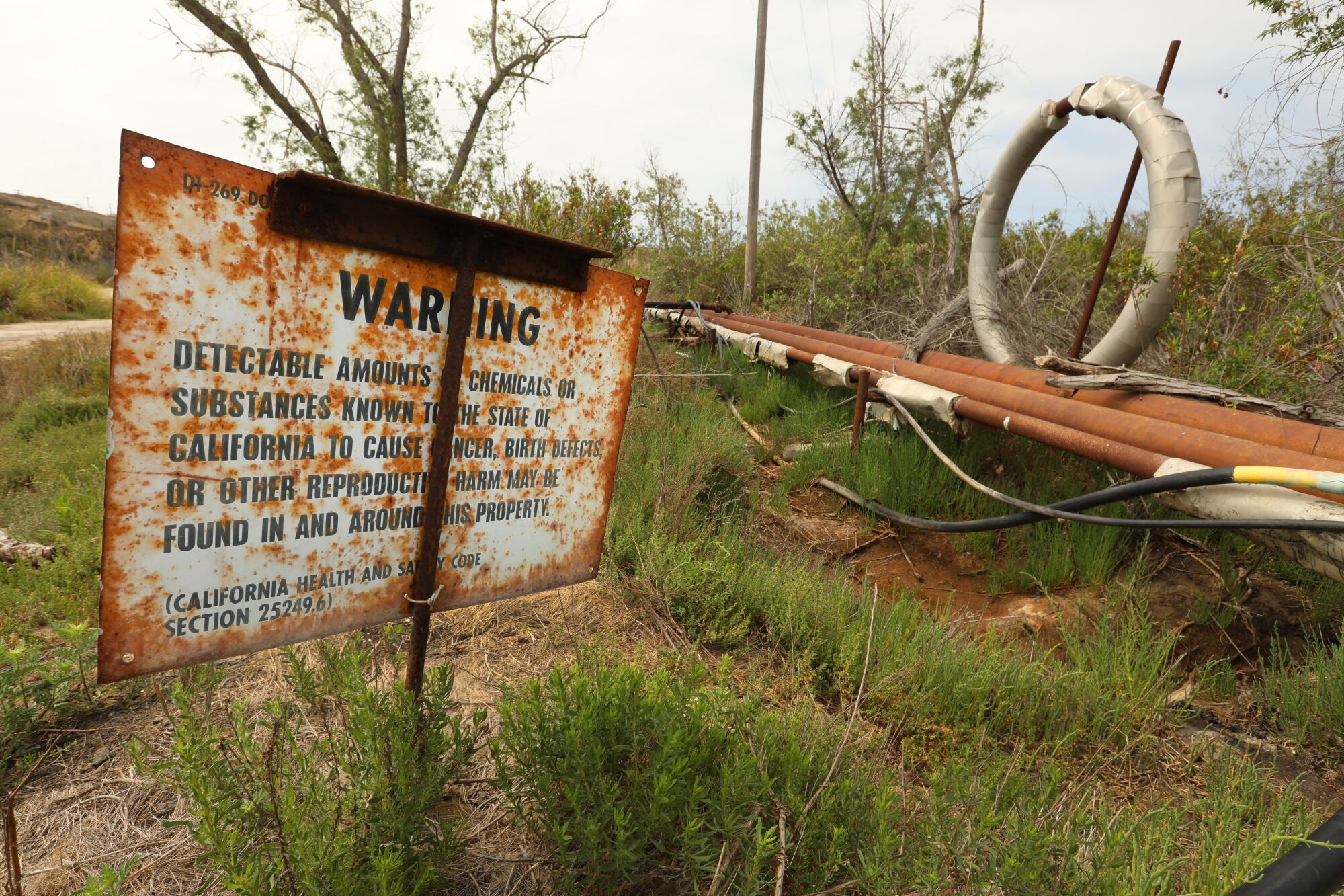 A rusty sign warns of hazardous materials at Banning Ranch property.