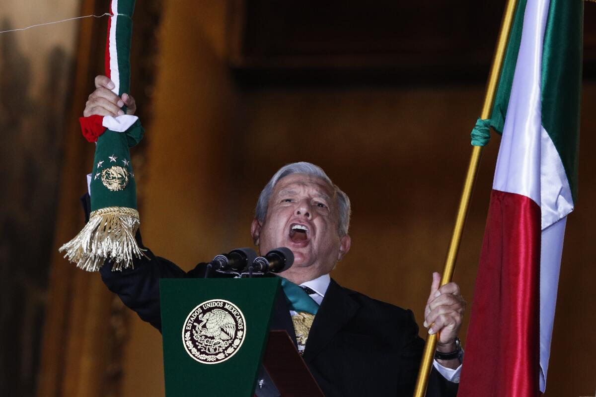 A main in a dark suit tugs on a tasseled bell pull while holding a red, white and green flag in his other hand 