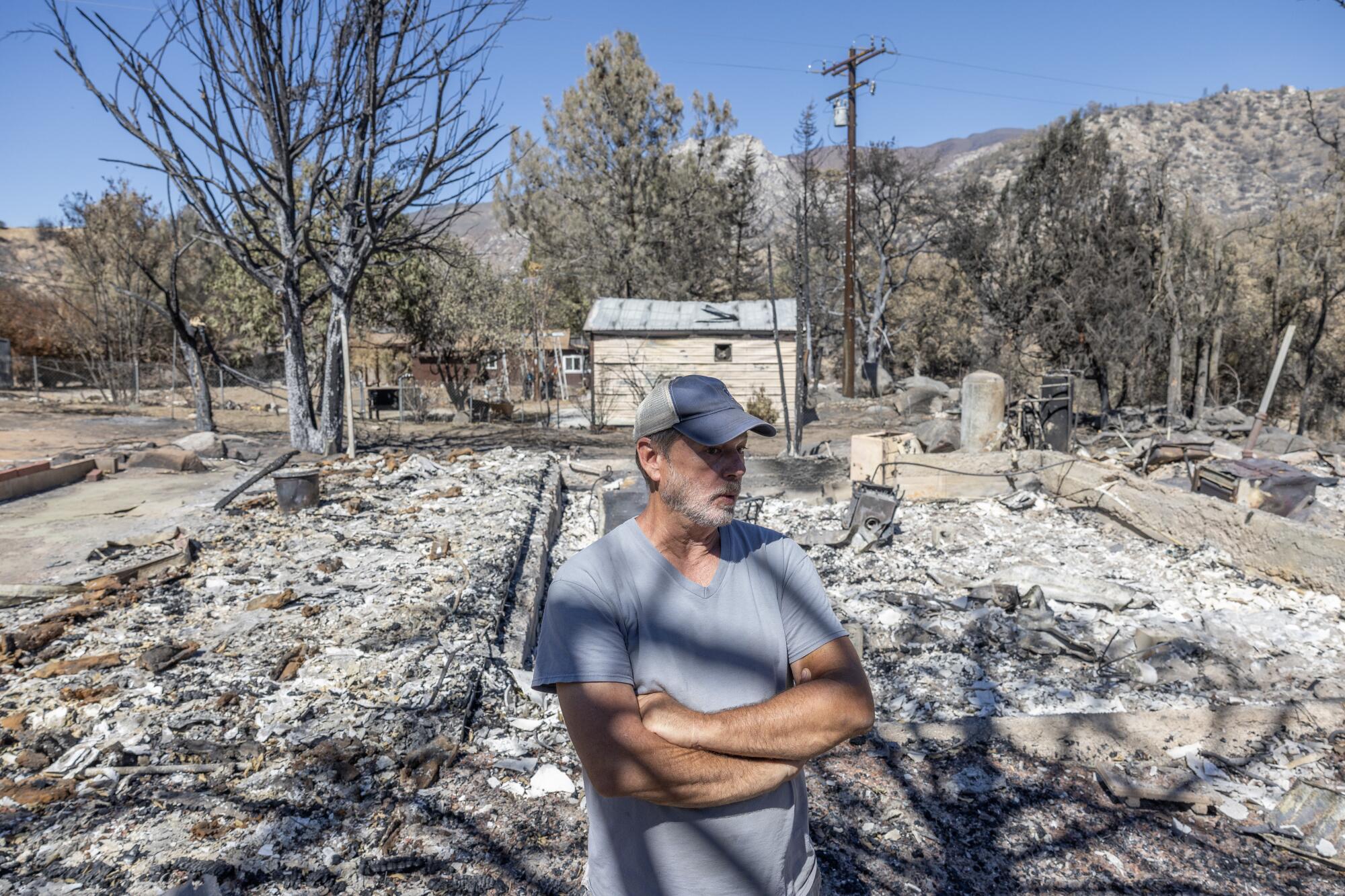 A man stands, arms crossed, amid a scorched white landscape. 