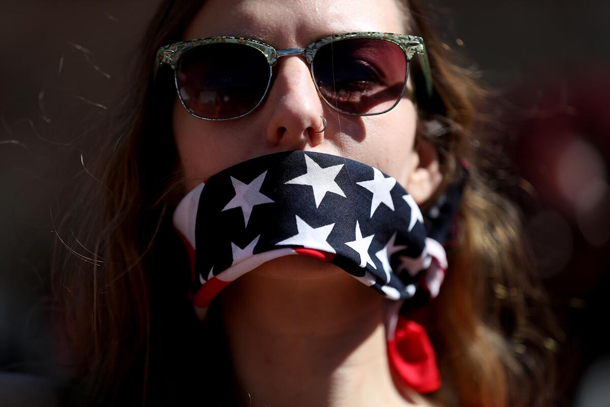 A protester wears a banda,na over her mouth during a rally to support women's health programs.