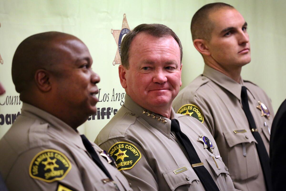 During a press conference Monday at the Hall of Justice, Los Angeles County Sheriff Jim McDonnell, center, smiles at deputies David Perry, left, and Adam Collette, who found an abandoned newborn baby inside a crevice along a bike path in Compton.