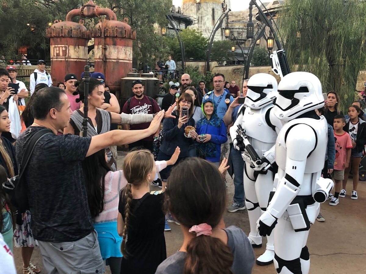 Rey leads a pack of guests to repel Stormtroopers in Star Wars: Galaxy's Edge.