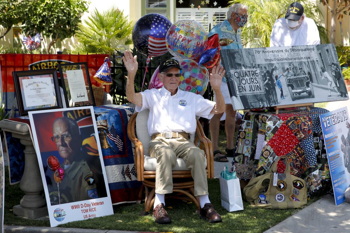 Tom Rice waves to friends while seated near balloons and war memorabilia