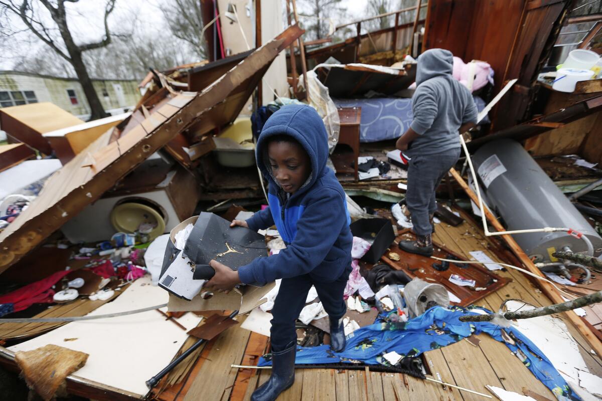 Emma Carter's grandsons comb the remains of her mobile home in Pickens, Miss., after severe weather hit the area on Thursday.