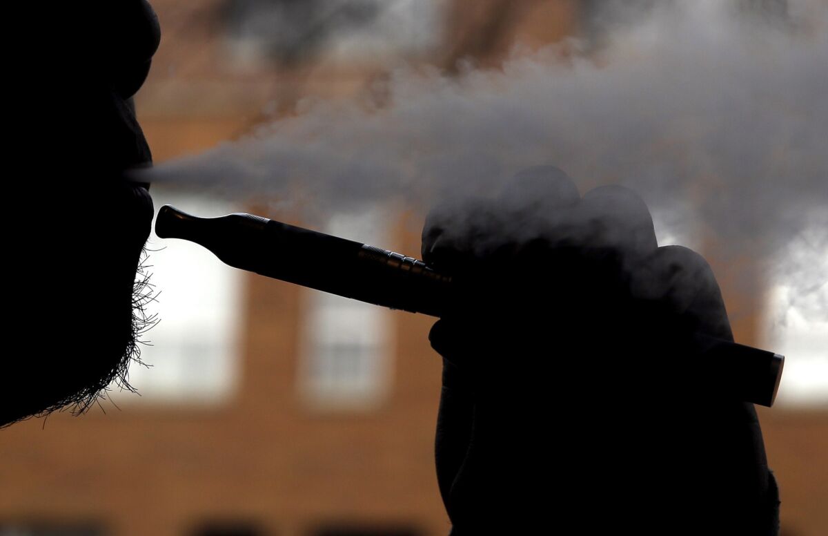 A smoker vapes with an e-cigarette.