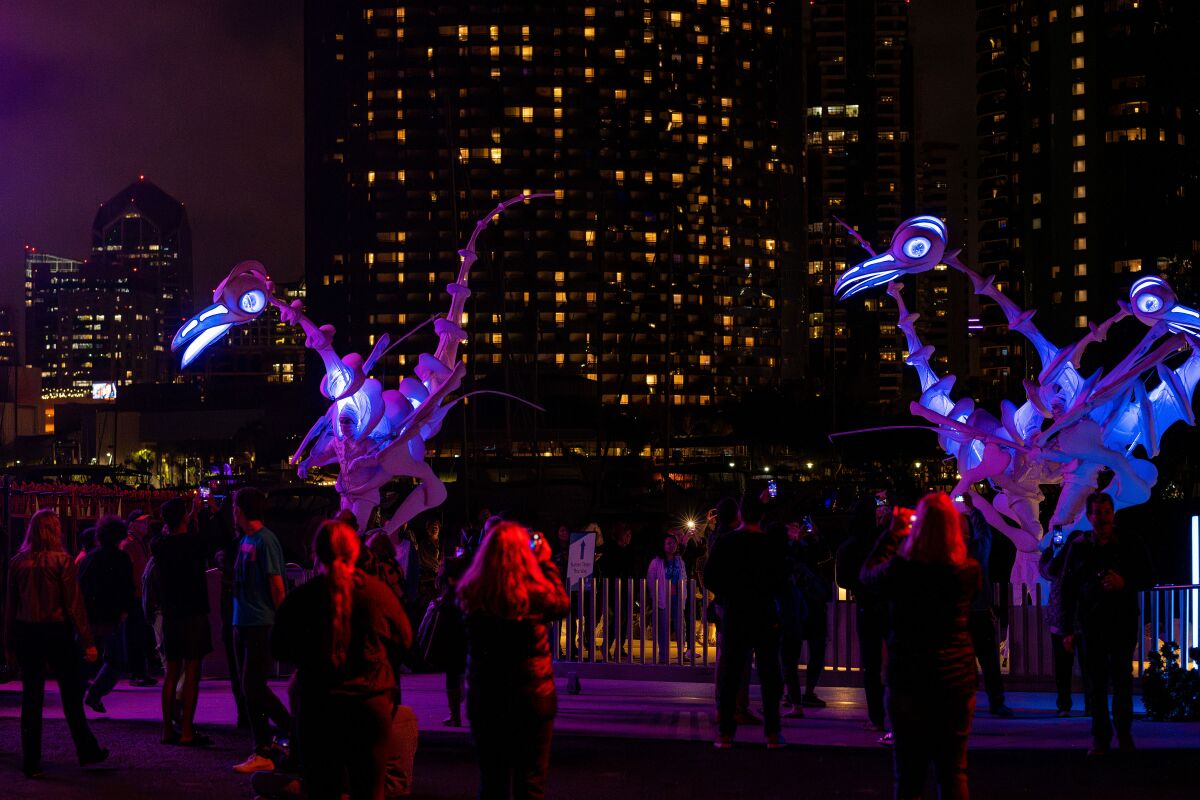 Stilt-walking puppets move through a crowd in "Birdmen."
