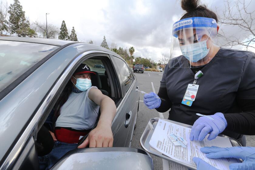 Medical Assistant Tracy Epperson prepares to give Comcino Calderon the Johnson and Johnson Covid vaccine as part of the Adventist Health mobile vaccination clinic parked outside a Walmart on Fashion Plaza Thursday morning.