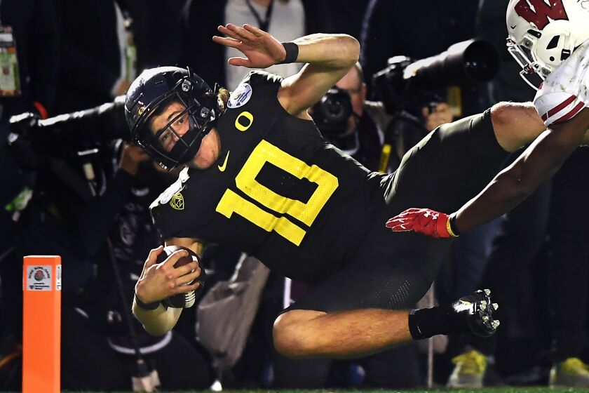 PASADENA, CALIFORNIA JANUARY 1, 2020-Oregon quarterback Justin Herbert scores the go-ahead touchdown against Wisconsin cornerback Faion Hicks in the 4th quarter at the Rose Bowl in Pasadena Wednesday. (Wally Skalij/Los Angerles Times)