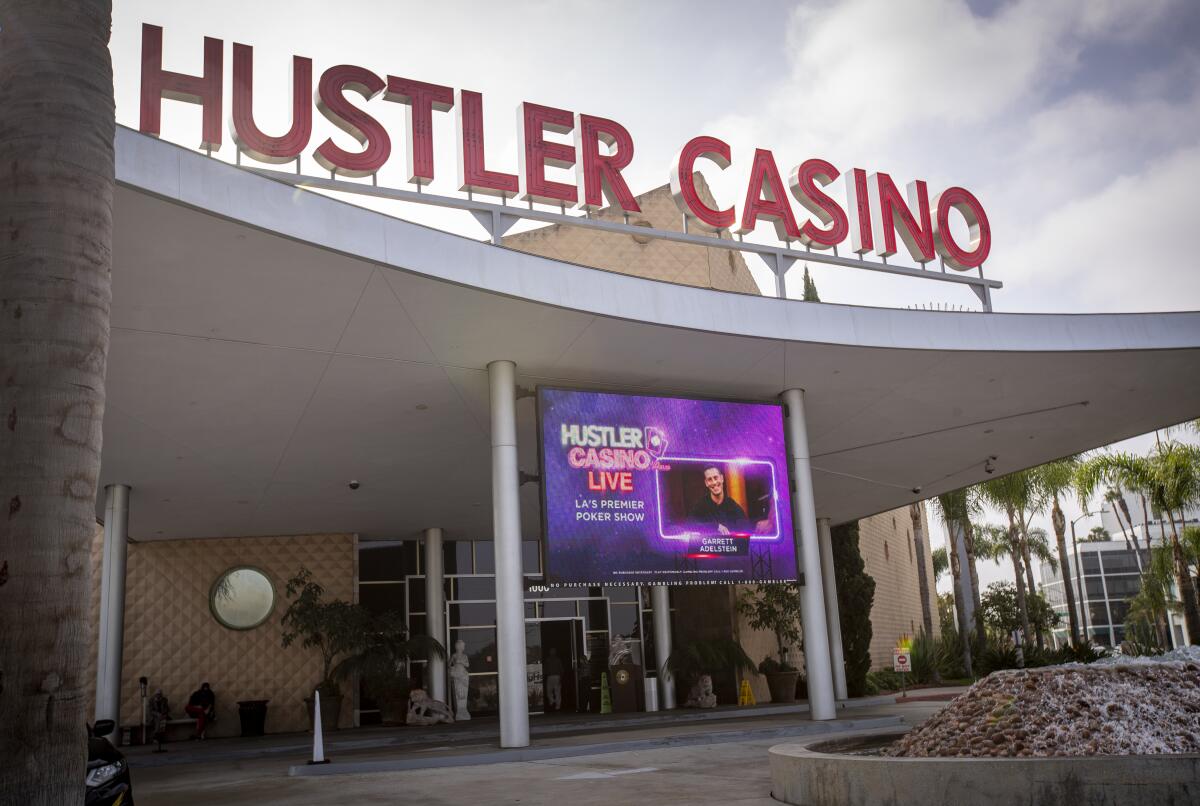 A big screen hangs outdoors under the Hustler Casino sign.