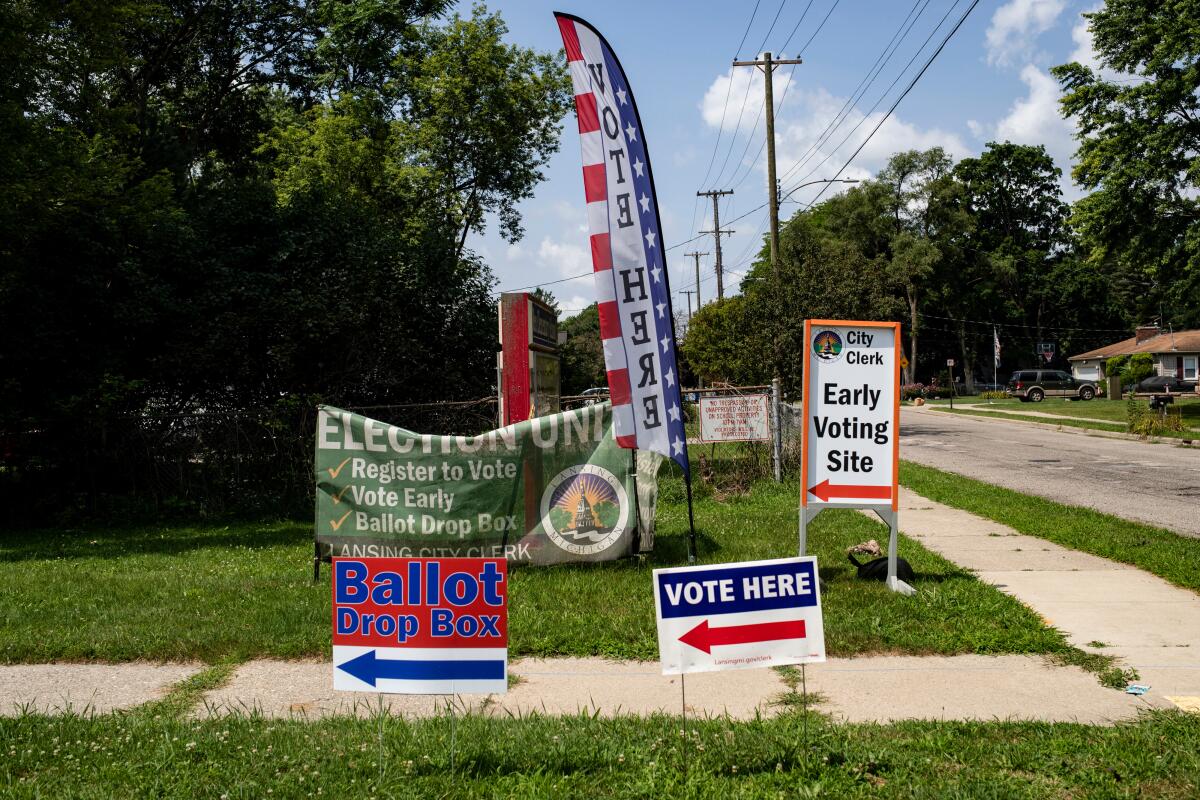 Voting signs posted in grass along a sidewalk