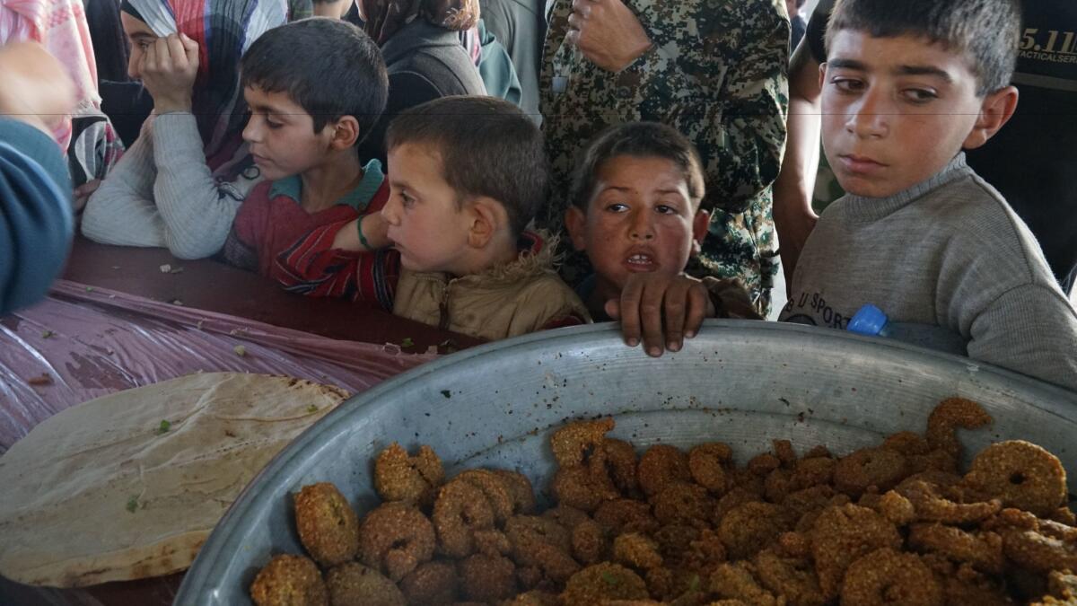 Survivors of a car bombing at the abandoned industrial complex of Jibreen on the outskirts of eastern Aleppo, in a meal line on April 16, 2017.