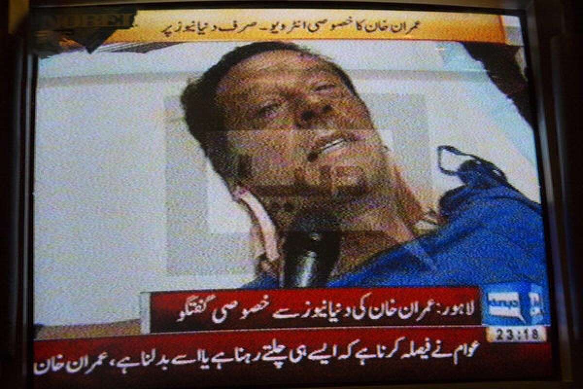A television station shows an image of former cricketer Imran Khan giving an interview after he suffered a fall during an election rally in Lahore, Pakistan.