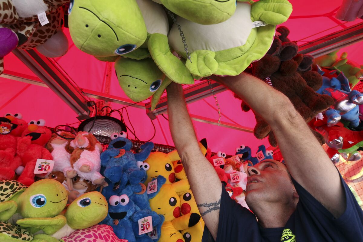 Michael Gilliam puts up stuffed animal prizes at the Balloon Pop carnival game at the San Diego County Fair on Thursday at the Del Mar Fairgrounds. The fair opens Friday, May 31.