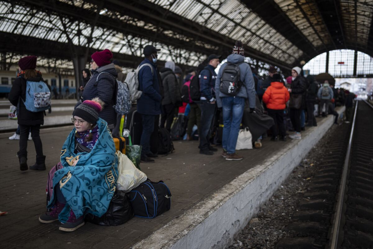 A child wrapped in a blanket sits among passengers at a train station in Lviv, Ukraine.