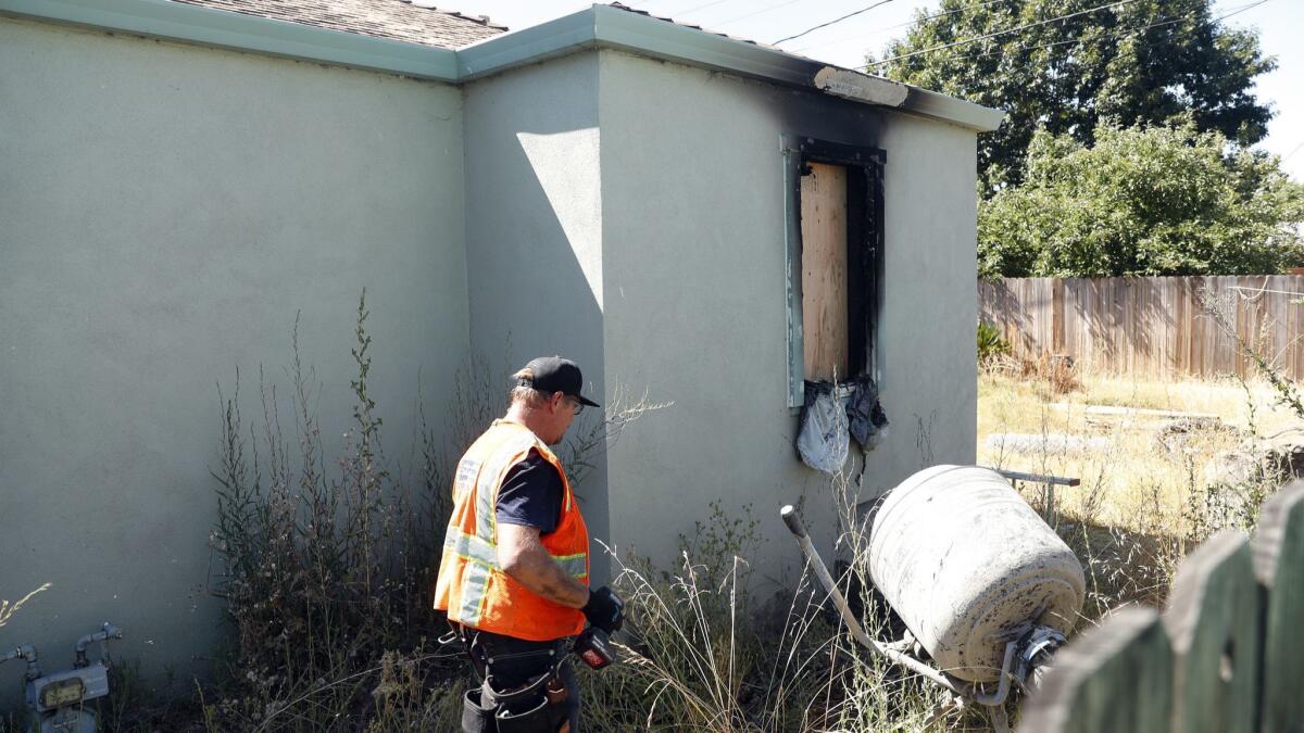 Construction crews work at a house in Vallejo, Calif., where police say a woman set herself on fire, killing herself and her twin 14-year-old daughters.