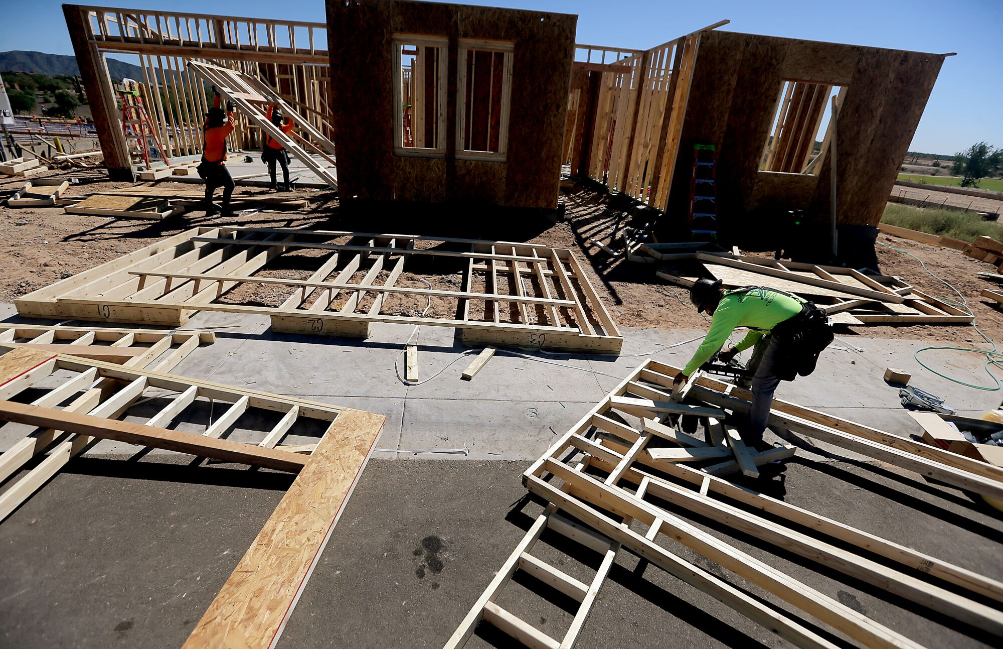Construction workers erect new homes in a dry landscape
