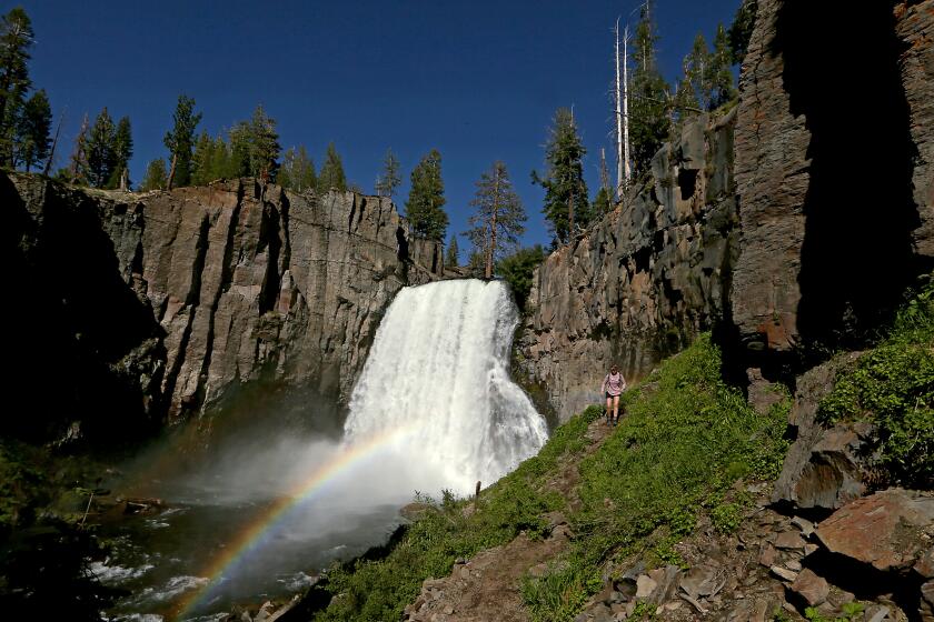 Mammoth Lakes, CA - Hikers follow a trail along Rainbow Falls in the Devil's Postpile National Monument near Mammoth Lakes on Thursday, July 27, 2023. The falls are fed by the middle fork of the San Joaquin River, which is running strong after last winter's record snowfall in the Sierra Nevada. (Luis Sinco / Los Angeles Times)
