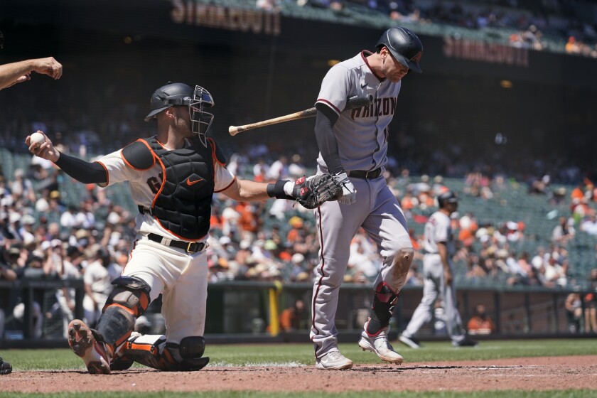 Arizona Diamondbacks' Carson Kelly walks back to the dugout after striking out swinging against San Francisco Giants starting pitcher Kevin Gausman during the seventh inning of a baseball game Thursday, June 17, 2021, in San Francisco. At left is Giants catcher Curt Casali. (AP Photo/Eric Risberg)