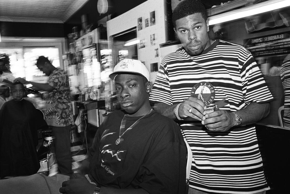 A black-and-white image of two young men inside a barber shop 