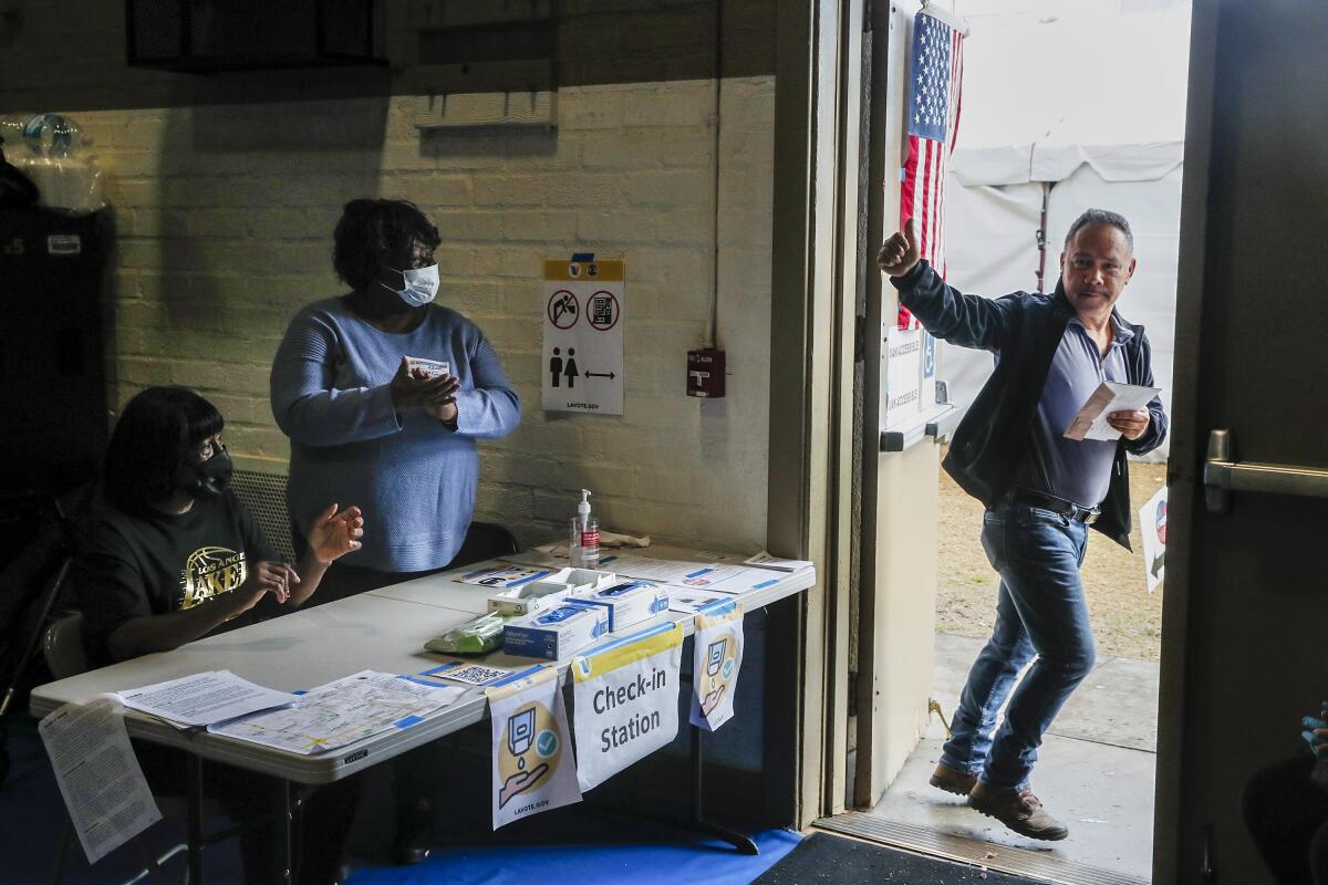 Two women at a table, left, applaud as a man gives a thumbs-up in a doorway