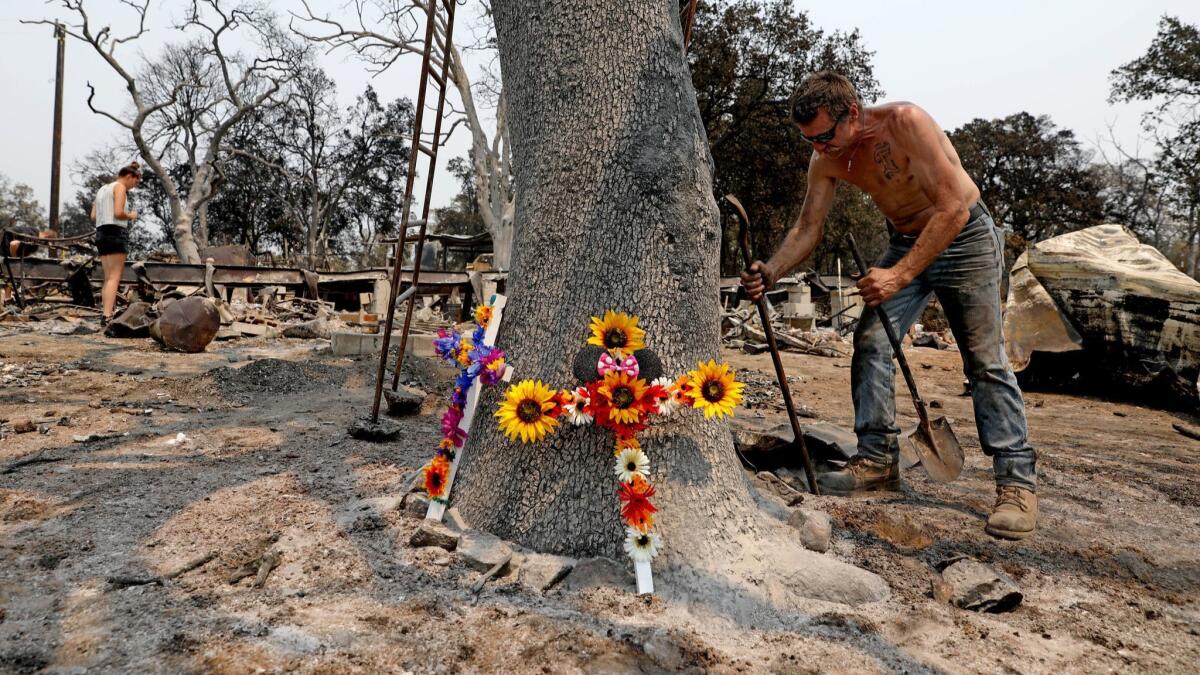 Brian Bledsoe, 52, son of deceased Melody Bledsoe, 70, works around a memorial of three crosses placed by Amanda Woodley, left, a granddaughter of Melody, on his father's property, damaged by the Carr fire in Redding on Aug. 4.