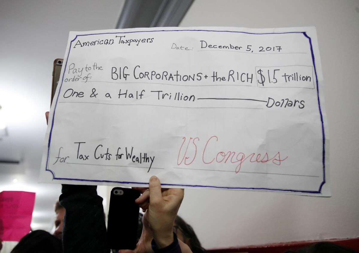 A man holds up a sign protesting the GOP tax plan on Capitol Hill.